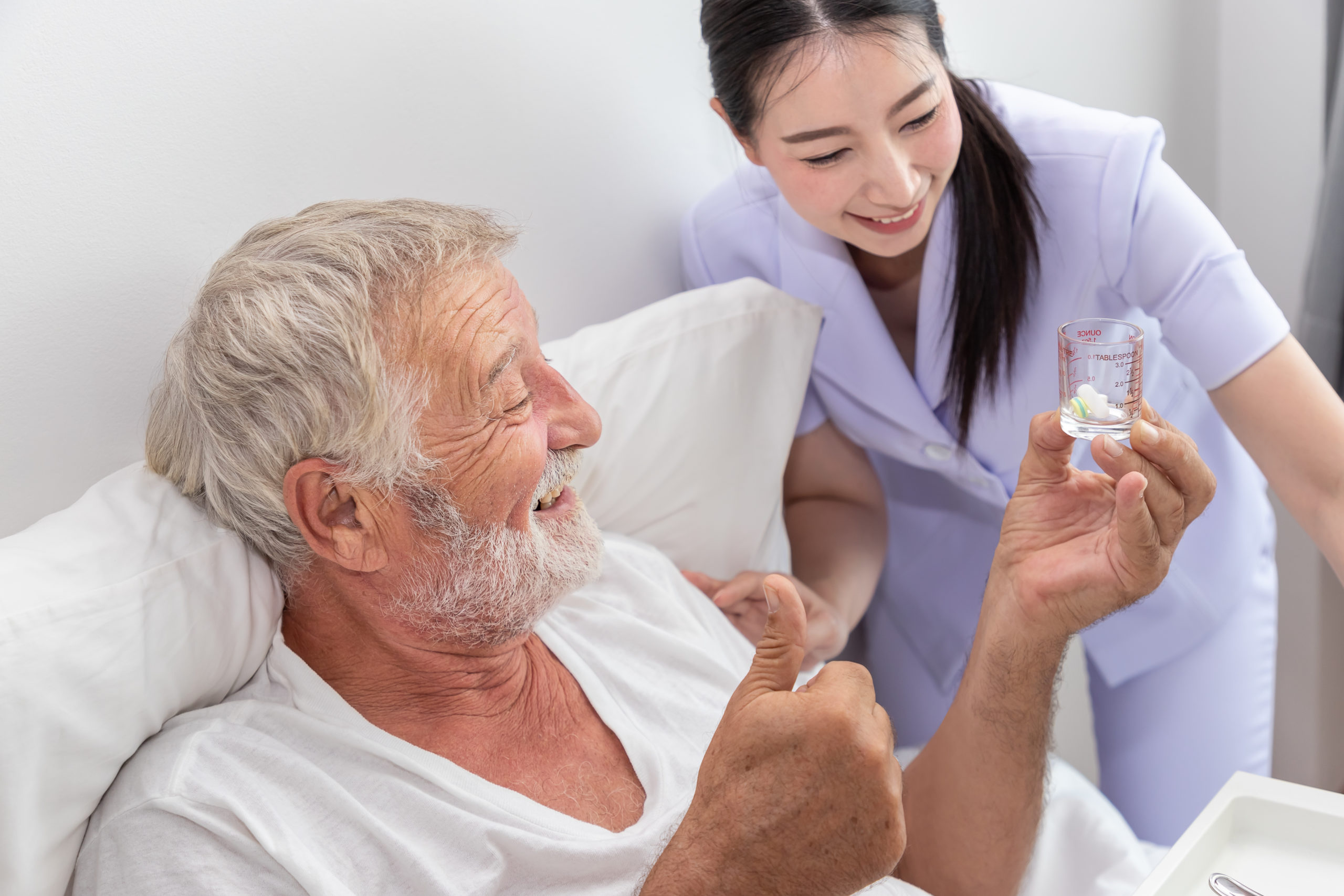 Happy nurse give pills, assist, and encourage elderly senior man